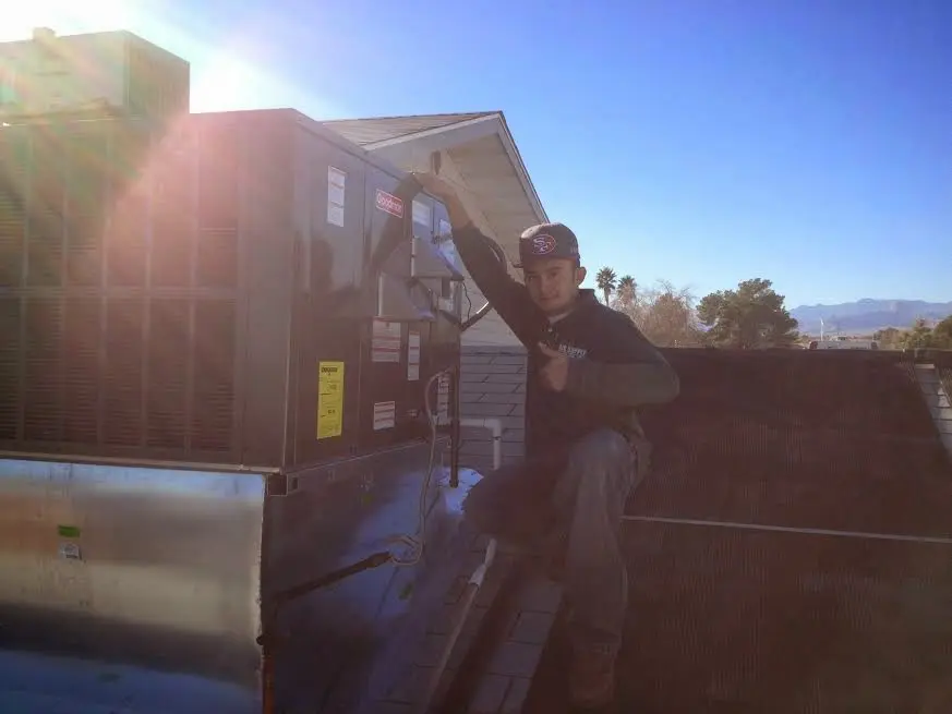 HVAC technician performing Air Duct Cleaning on a rooftop unit in Hoschton