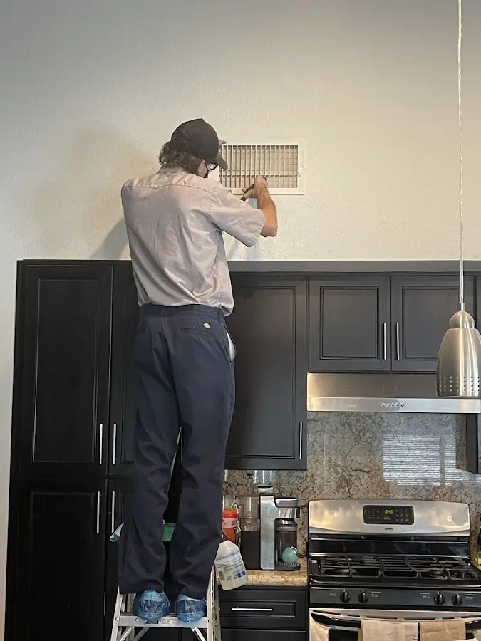 Technician inspecting an air vent during HVAC service in Hoschton